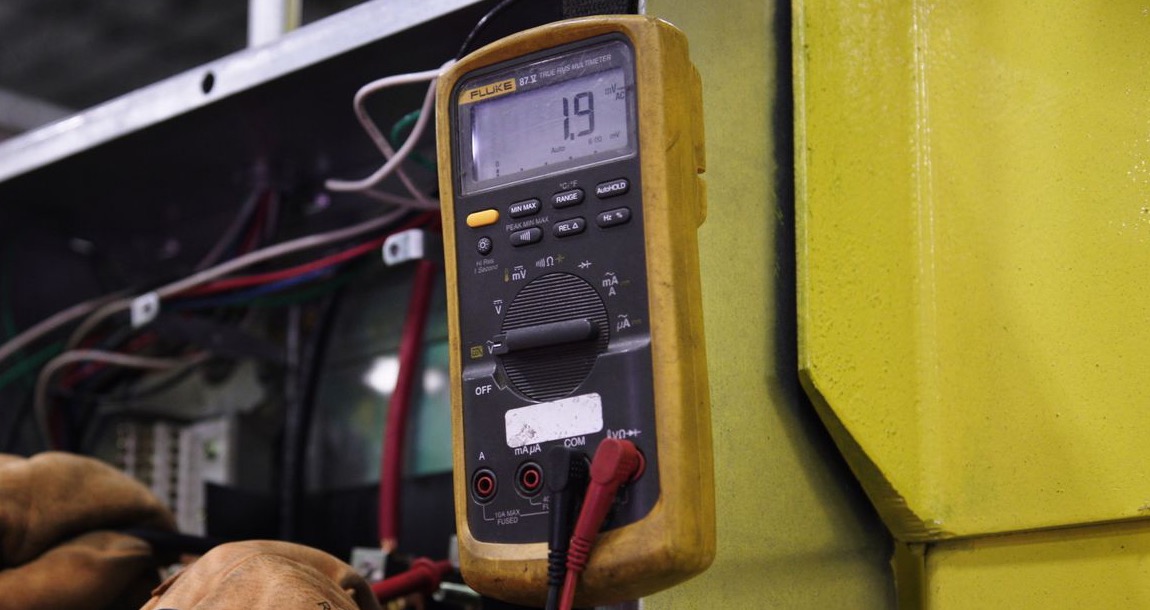 Électricien mesurant un coffret électrique au multimètre